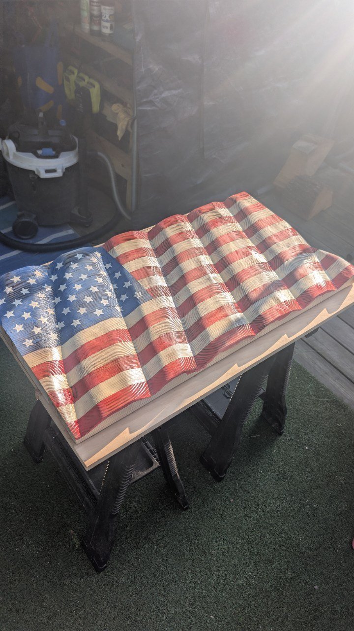 Sculpted 3D waving wooden American flag showing detailed ripple carving and vibrant grain